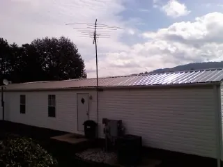 New metal roof on a single wide mobile home with a TV antenna in Grover