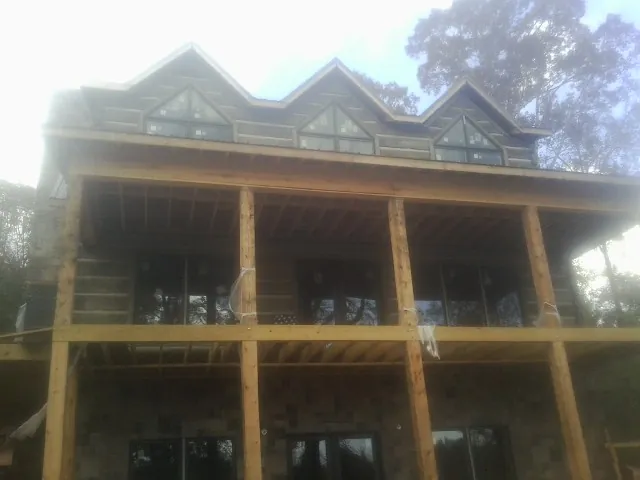 Dormers and porch framing on a large log home under construction — Roof Coating work by our crew in Grover
