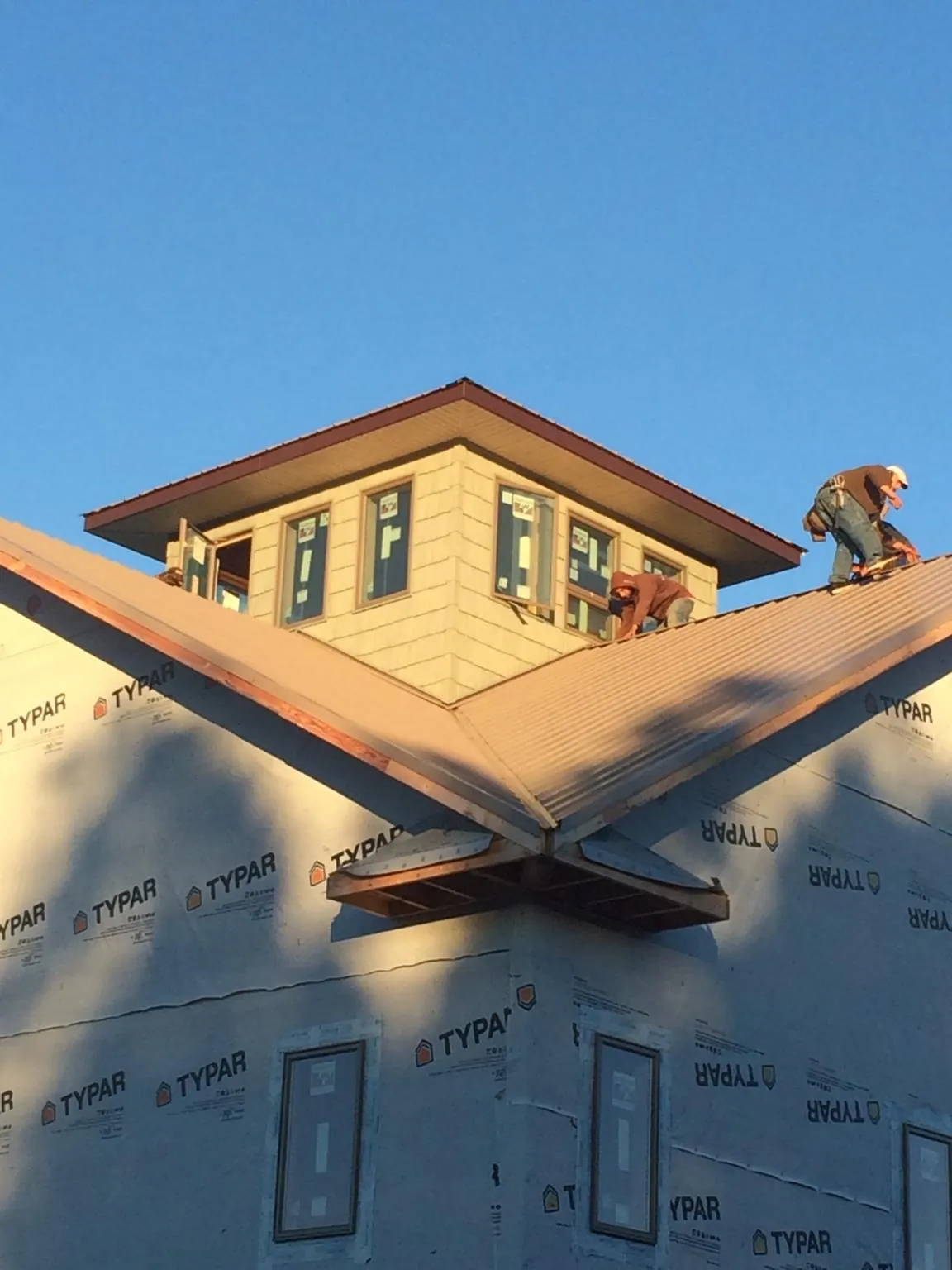 Roofers working around a rooftop cupola on a new metal roof at sunset — Roof Waterproofing in Grover by Roofing Brothers